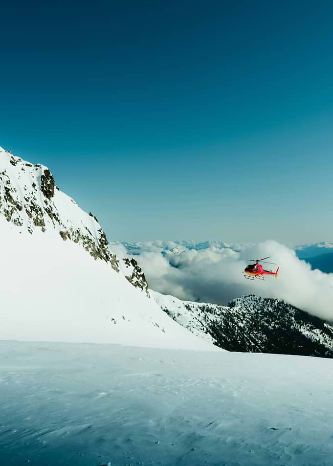 Red Helicopter Over Snowy Mountains