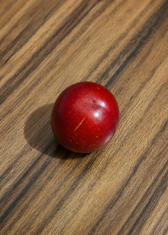 Single Red Plum on Wood Surface