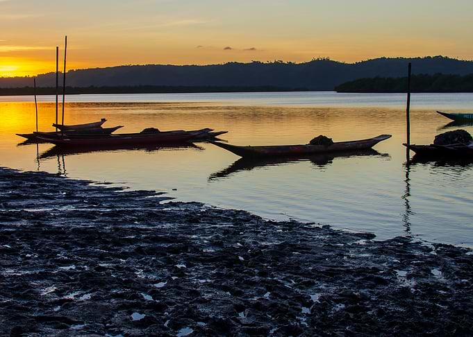 Sunset over calm river with boats