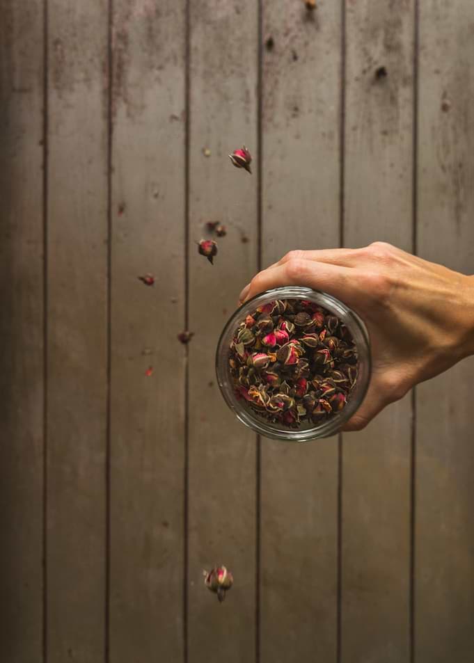 Hand Holding Jar of Dried Rosebuds
