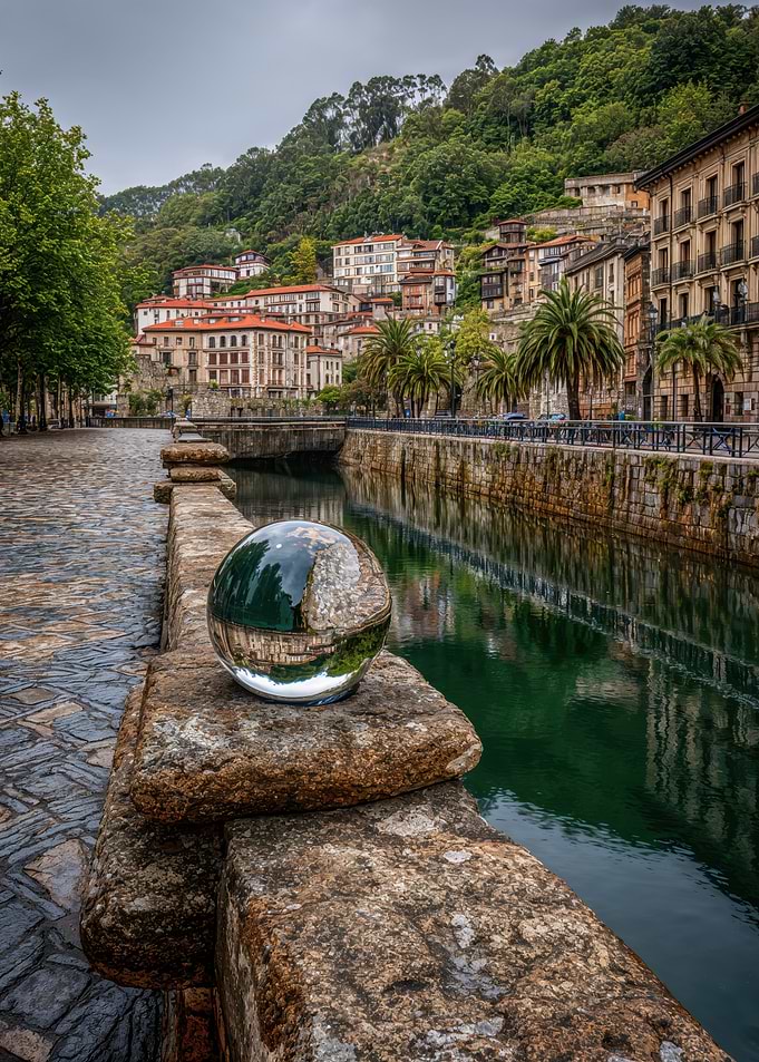 Glass sphere on stone bridge reflecting town