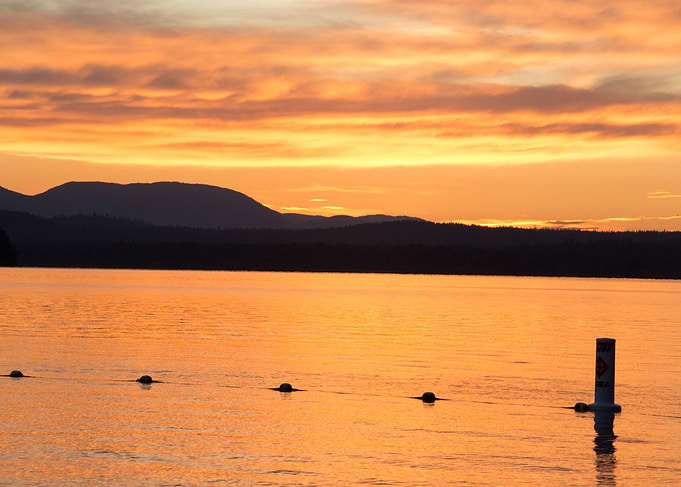 Silhouetted distant hill and a calm lake