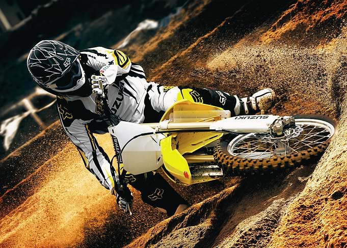 Suzuki Motocross Rider Cornering on Dirt