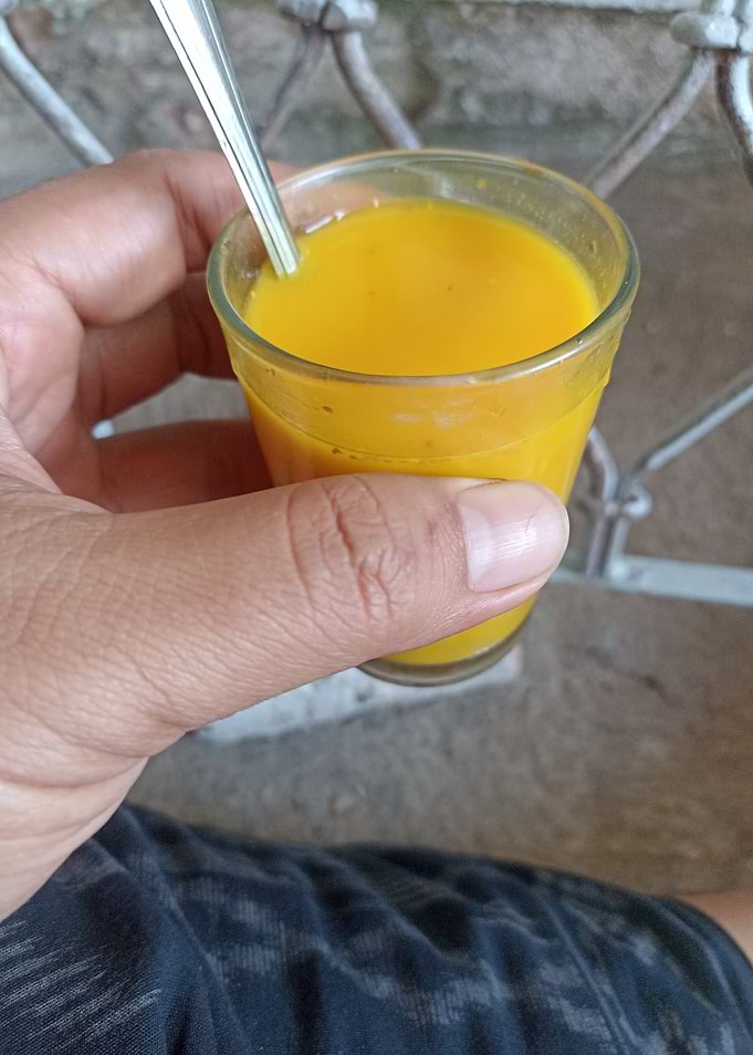 Hand Holding Glass of Mango Juice
