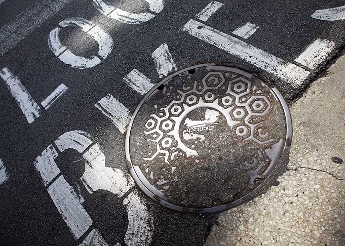 Manhole Cover on Painted Asphalt