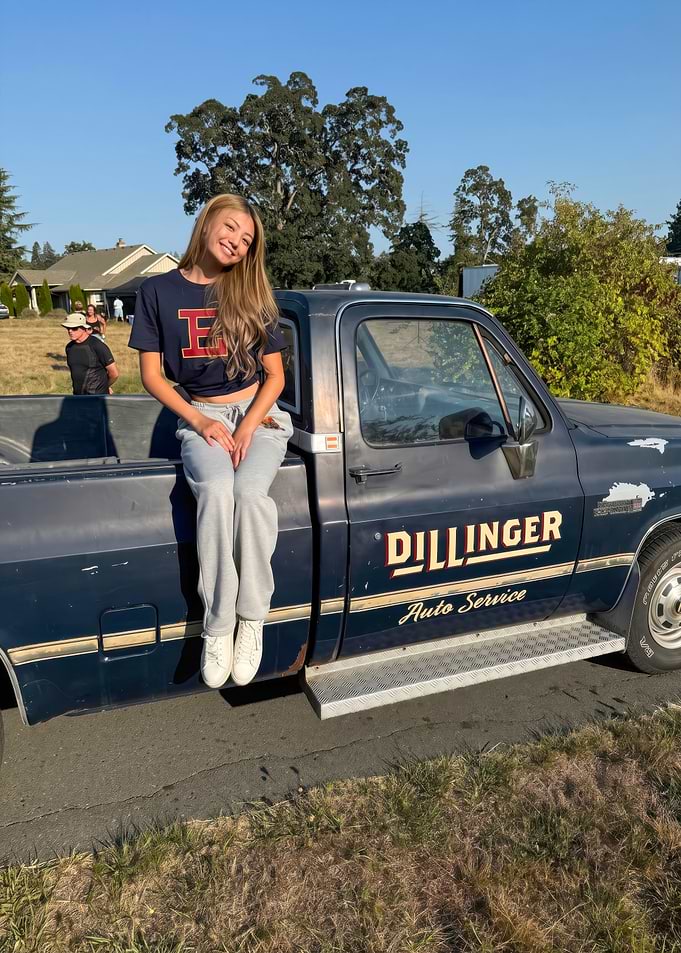 Young woman sitting on vintage truck