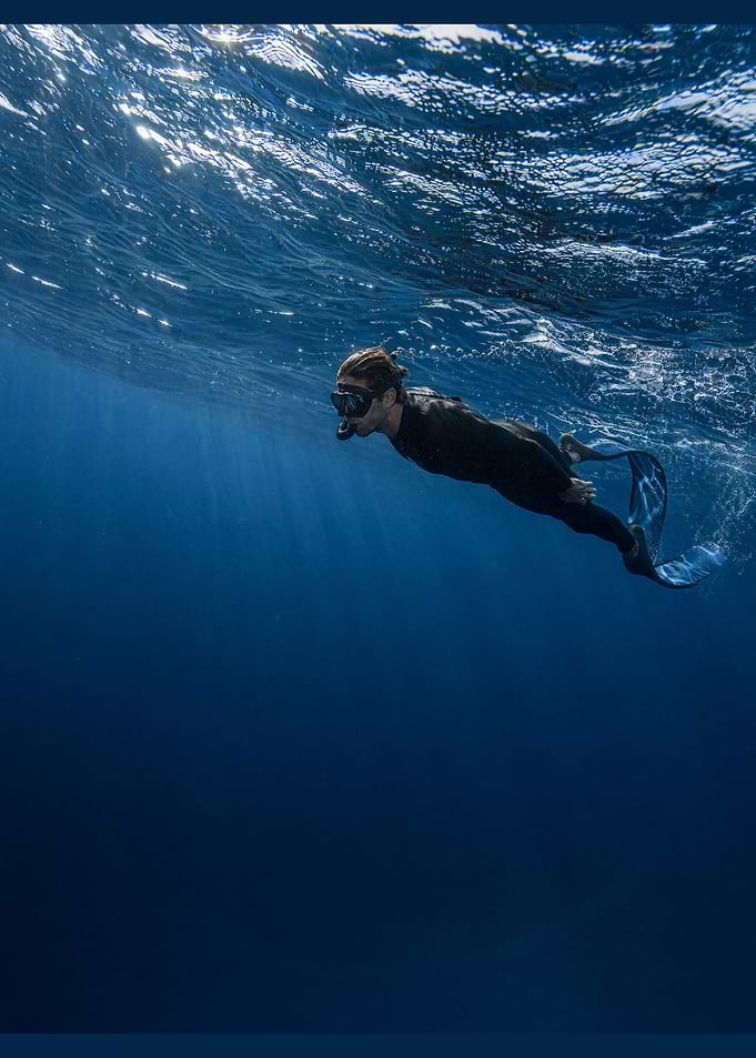 Freediver swimming in deep blue ocean