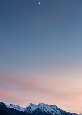 Snow covered peaks under the moon just after sunset