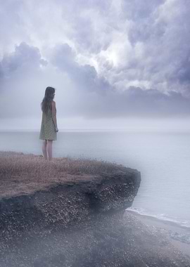 a girl standing on the edgle of a cliff over a foggy se ...