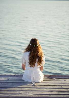 A blonde girl sitting from behind, look at the sea