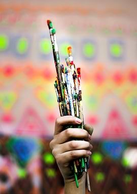 Photograph of a hand holding some colorful dirty art br ...