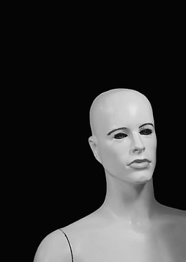 A bald, black and white manikin / mannequin against a b ...