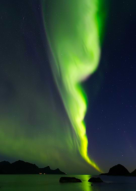 Northern Lights reflecting in water surrounded by mountains