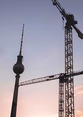 Berlin, Germany I Fernsehturm tower silhouette and cranes in pastel pink and blue sunset sky light for a minimal industrial cityscape photography with golden hour glow and geometric urban composition