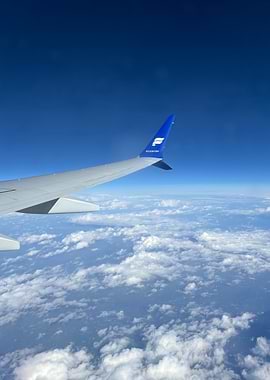 Airplane wing over clouds and sky