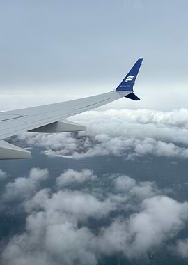 Airplane wing over clouds and ocean