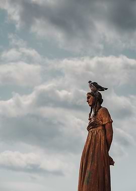 Statue with Pigeon Against Cloudy Sky