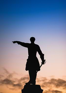 Silhouette of Statue Against Colorful Sky
