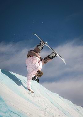 Snowboarder performing handstand on snowy ramp