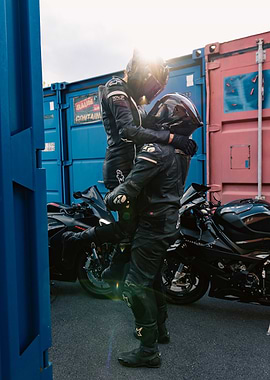 Motorcycle riders embracing near shipping containers
