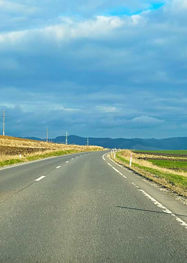 Road Through Countryside Under Cloudy Sky