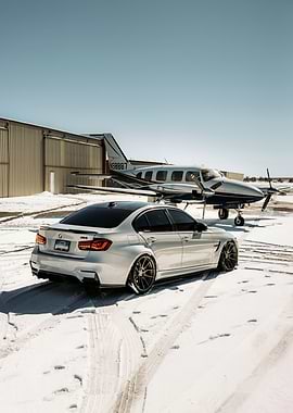 Silver BMW and Airplane on Snowy Ground