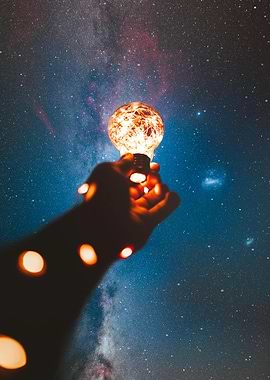 Hand holding lightbulb against starry sky