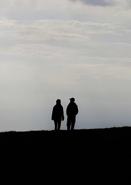 Silhouetted couple walking on a hill