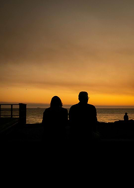 Silhouette of couple watching sunset over ocean