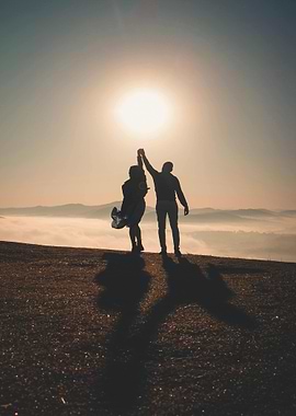 Silhouette of couple holding hands at sunrise