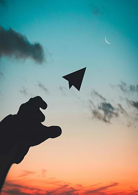 Paper airplane silhouette against sunset sky