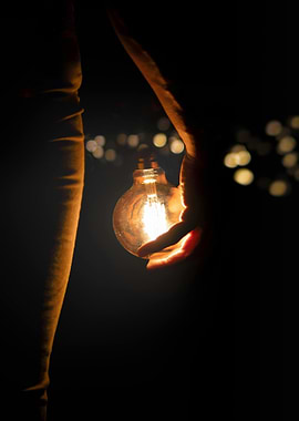 Hand holding a glowing light bulb