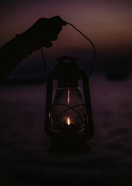 Hand holding a lit lantern at dusk