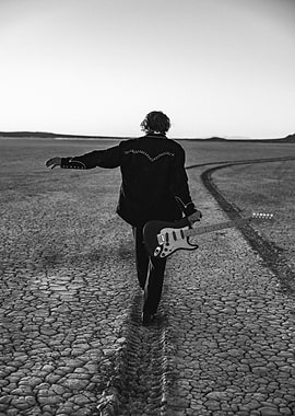 Guitarist walking in desert landscape