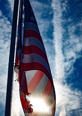 Tattered American Flag Against Cloudy Sky