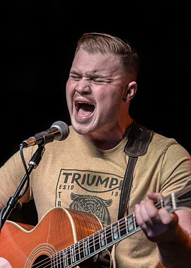 Singer performing with acoustic guitar zach bryan