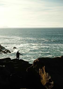 Silhouette of fisherman on rocky coast