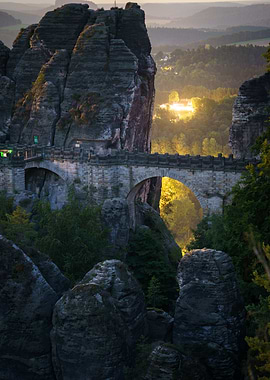 Bastei Bridge with stones in the foreground and a village in the background at night