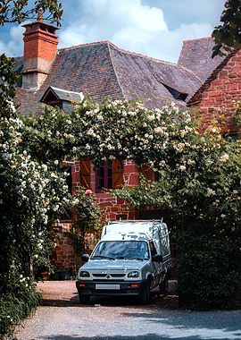 Van parked in front of a floral-covered stone house
