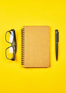 Notebook, Glasses, and Pen on Yellow Background
