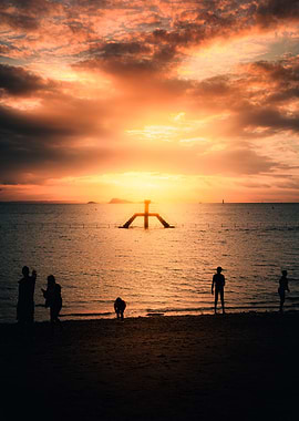 Sunset over the ocean with people on the beach