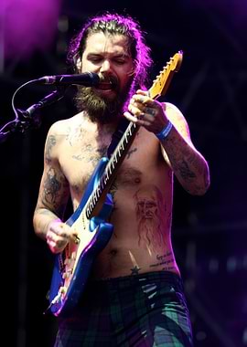 Shirtless guitarist with beard and tattoos