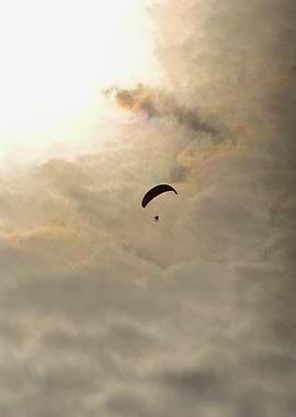 Paraglider soaring through colorful clouds