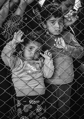 Children behind a fence in a refugee camp in Rojava