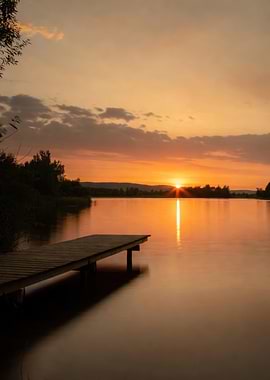 Sunset over a calm lake with a wooden dock