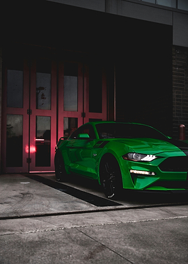 Green Ford Mustang parked by red doors