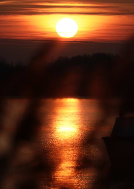Sunset over a calm lake with a boat