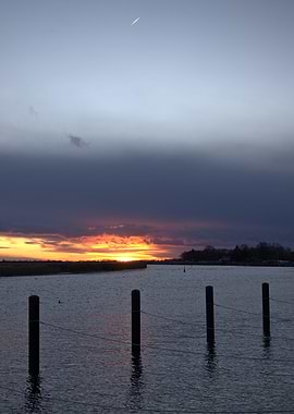 Sunset over a calm bay with wooden posts