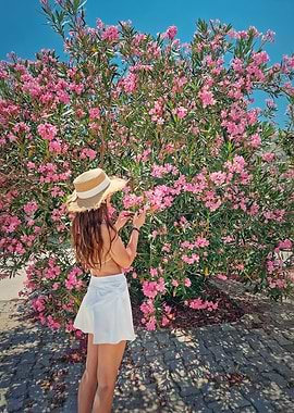 Woman in straw hat by pink flowers