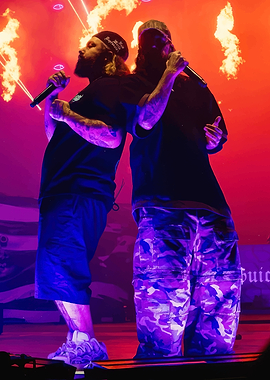 Two rappers performing on stage with fire effects